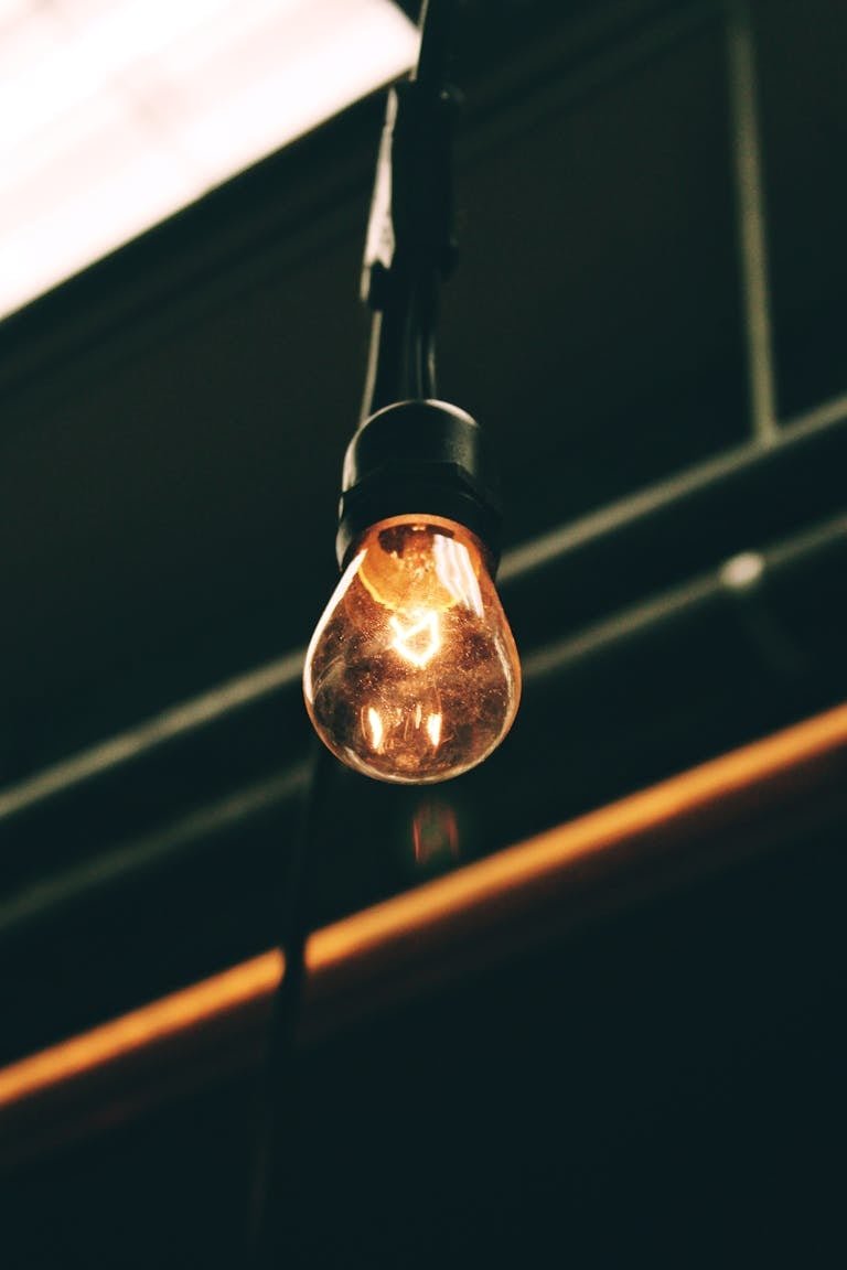 Close-up of a glowing vintage incandescent light bulb hanging indoors, casting a warm ambiance.
