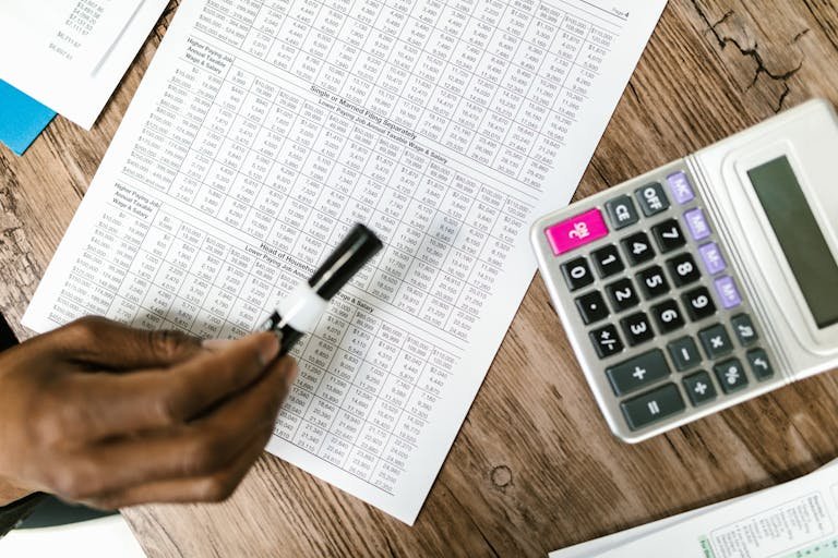Close-up of tax documents and calculator on wooden table, highlighting financial analysis.