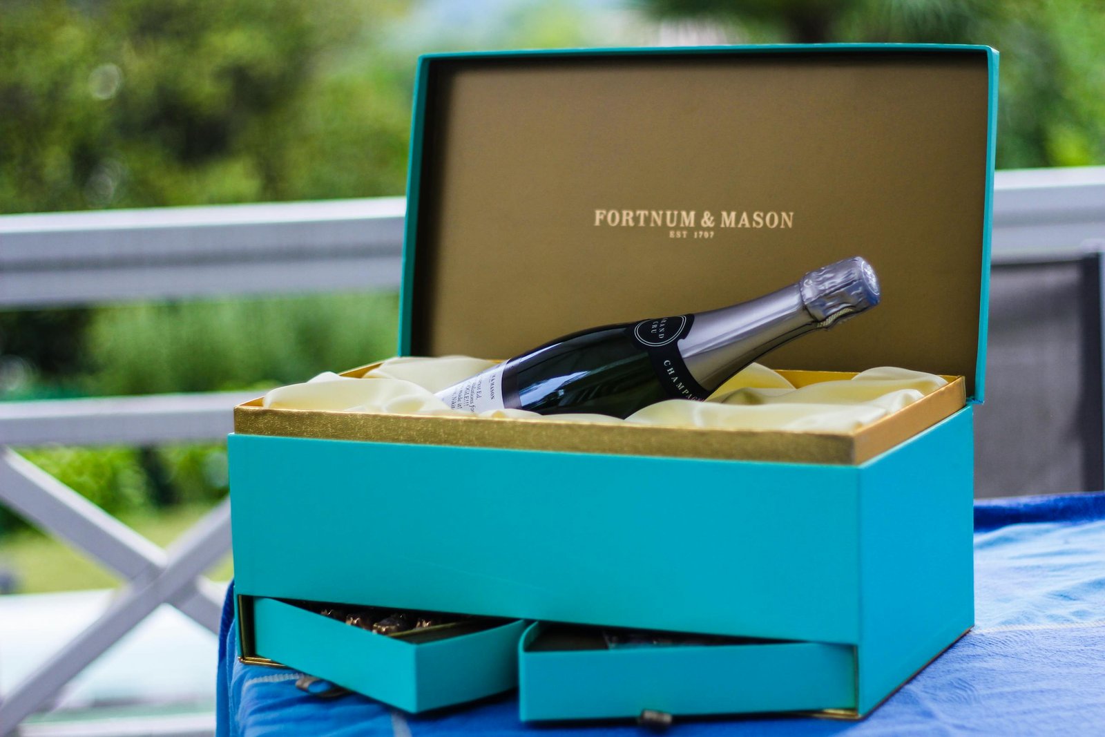 Elegant Fortnum & Mason gift with champagne bottle on table outdoors.