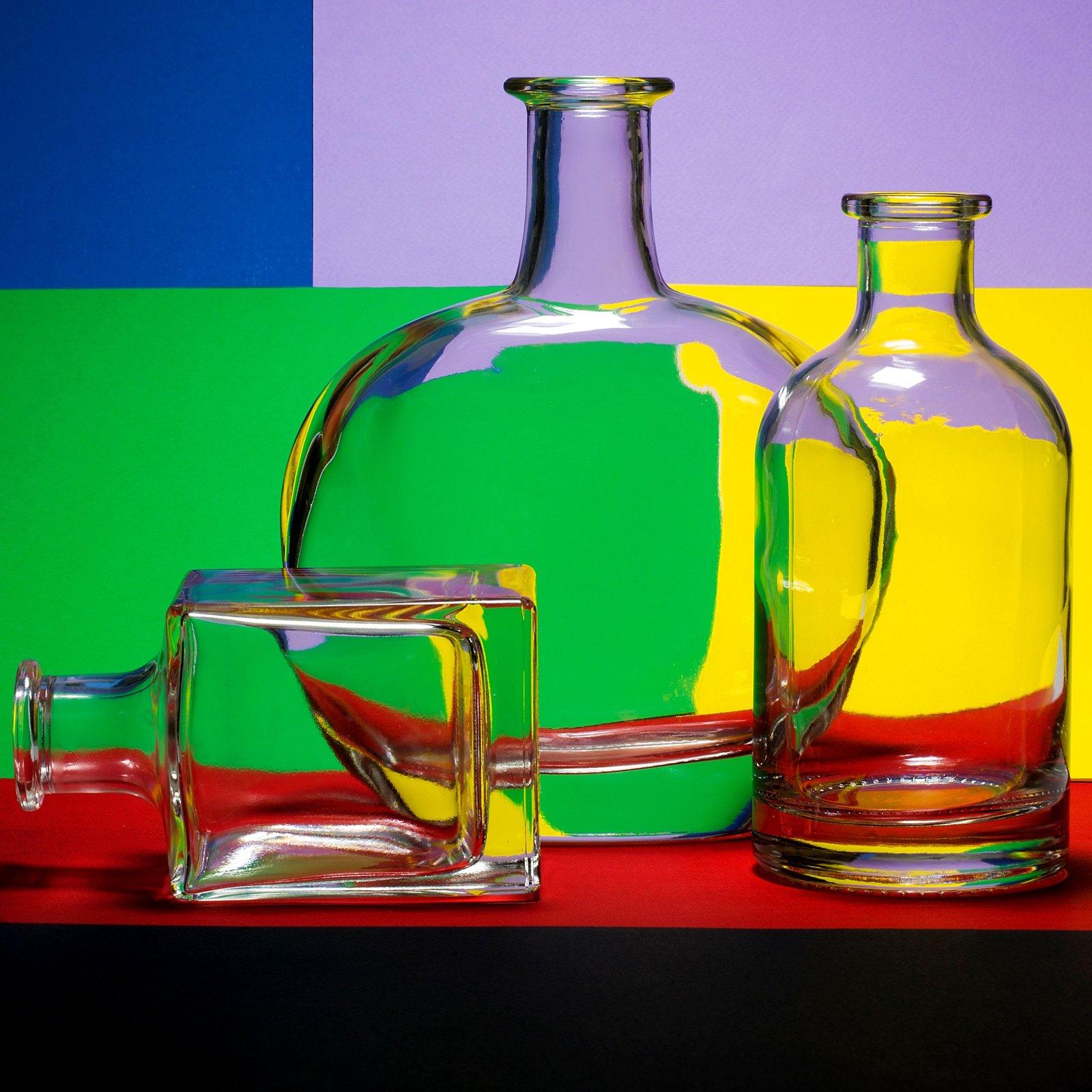 Glass bottles with a colorful geometric background creating a vibrant still life composition.